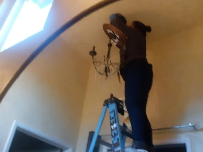Electrician installing a chandelier in a Bull Run residence